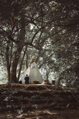 white wigwam teepee tent in a lush forest with a loneliness person sitting nearby © Photo-Panaioto