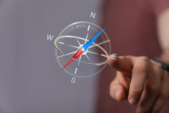 A hand pointing towards a transparent compass, representing direction, navigation, and guidance. Symbolic for finding yo