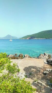 Empty sun loungers facing turquoise Adriatic with Mamula island and mountain horizon in Montenegro. Symbolizes luxury minimalism aesthetic, summer resort advertising, and peaceful seaside atmosphere.