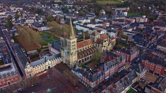Cath&eacute;drale Saint Pierre de Lisieux in Normandy, France, dominating historic town center with Gothic nave, transept and tall spire surrounded by red brick building and square, slow drone push in shot
