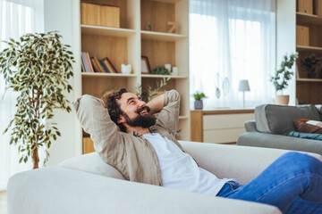 Relaxed Man Reclining On Couch In Bright Living Room Enjoying Leisure Time At Home
