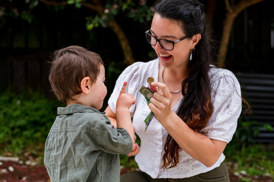 Toddler boy counting with mum using their fingers outdoors