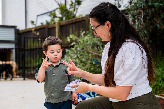 Toddler boy counting with mum using their fingers outdoors