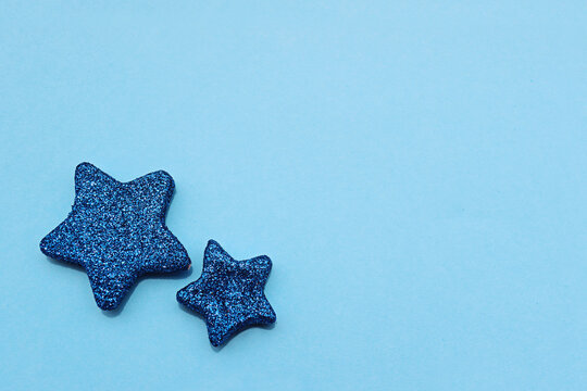 Two glittery blue star shapes resting on a soft blue surface, creating a simple and elegant background with a playful touch.