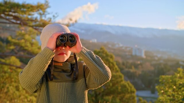 Small traveler looking through optical device in sunny park. Concept of environmental education, scouting skills, active lifestyle, and cognitive development.