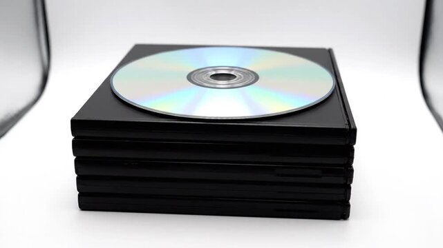 Stack of CDs on a black case with a single disc on top in a photography studio