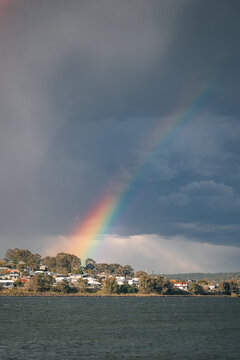 Stormy day by a lake with a rainbow reaching down to waterfront houses