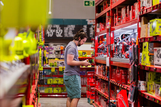 Man choosing product to purchase off shelf in hardware store shop