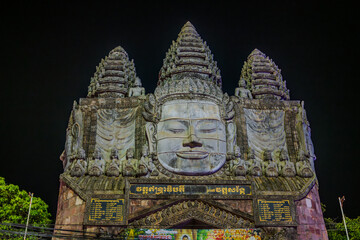 Obraz premium Illuminated Buddhist gate with stone faces at night in Siem Reap