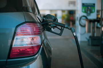 Primer plano de manguera de combustible surtiendo gasolina a un coche en una estación de servicio