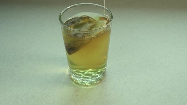 Making hot tea with a teabag being agitated in the water