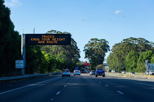 Trucks know your height and route digital sign above motorway with traffic passing by
