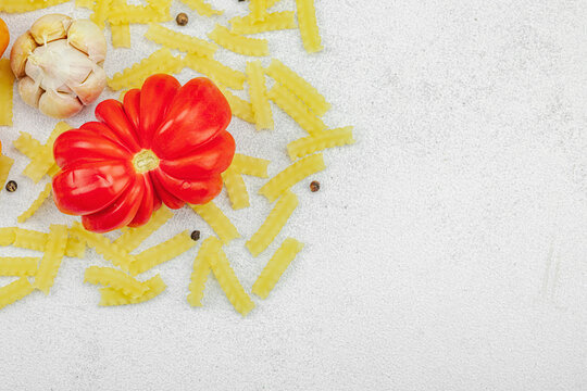 Raw mafalda corta pasta with assorted heirloom tomatoes, garlic, chili pepper, and spices