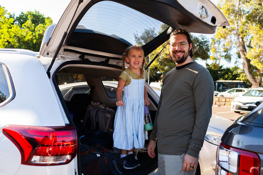 dad with daughter in the boot of car while on holiday in the city