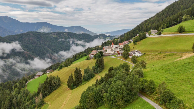 Aerial drone view of village, town Eores (Afers) near Bressanone (Brixen). Cloudy summer day. View on the Church of San Giorgio in the centre. Idyllic mountain village in the Italian Dolomites.