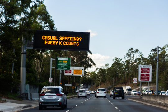 Out of focus "casual speeding? Every K counts" sign on digital signboard above road