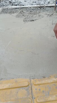 A bricklayer repairing a sidewalk with cement in the city of Sao Paulo_vertical.
