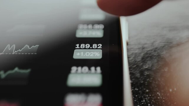 Financial data on mobile phone screen, current price for assets and percentage changes