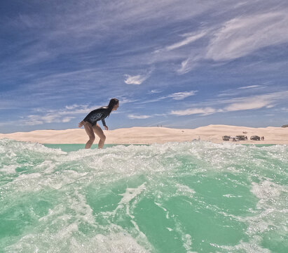 Female woman  surfer riding small waves on longboard  in summer wetsuit on sunny clear day