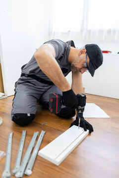 Handyman using cordless drill to assemble flat pack furniture