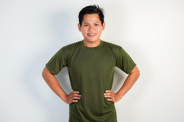 Confident Young Asian Man Smiling in Green Shirt With Hands on Hips Against White Background