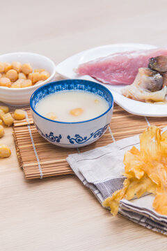A blue-patterned bowl of smooth congee with dried scallops and seafood, accompanied by pork and mushrooms.