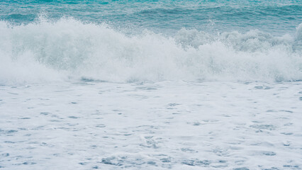 Obraz premium Ocean waves crashing on sandy beach with foam and turquoise water
