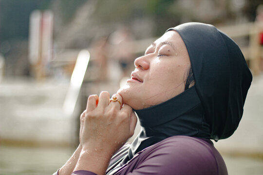 Hmong-American lifting head up with eyes closed and hands clasps together under the chin