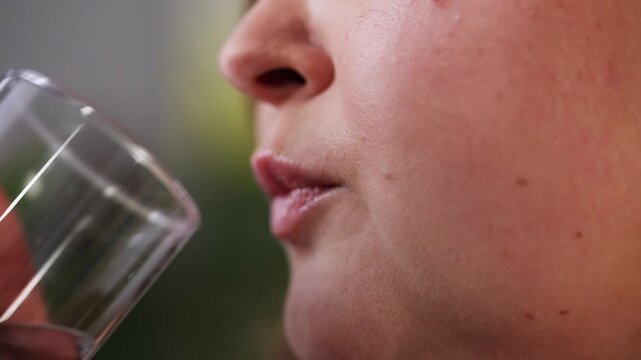 Close-up of positive plus size woman taking pill with water, dietary supplements