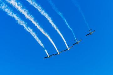 Group of aircraft planes in flight during airshow. Jets flying in the air. Airborne sport in thr sky with airplanes with blue background.