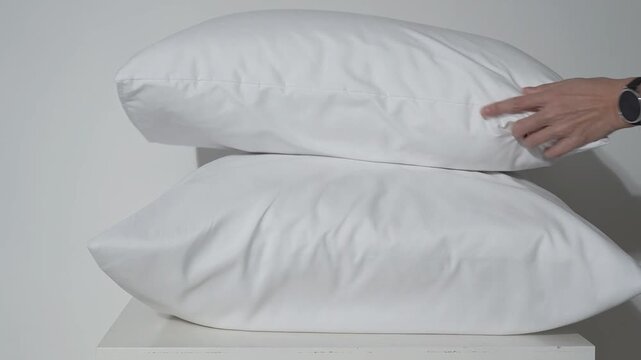 white pillows on the bed, female hands rearranging the bedclothes