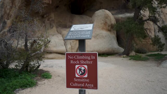 Signs in Joshua Tree National Park inform climbers about climbing rules and sensitive areas while exploring the rock formations.