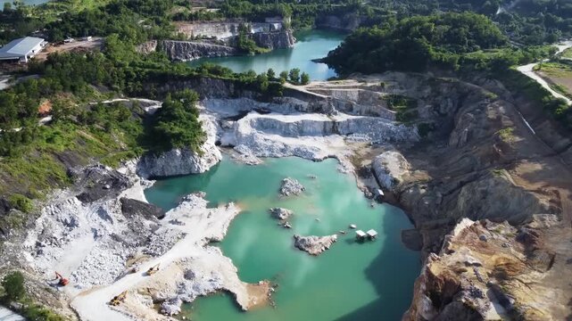 Aerial view of a turquoise lake within a quarry. The contrasting landscape shows the effect of human intervention on the environment