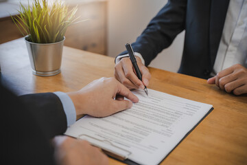 businessman sitting at desk holds pen signing contract paper, lease mortgage, employment hr or...