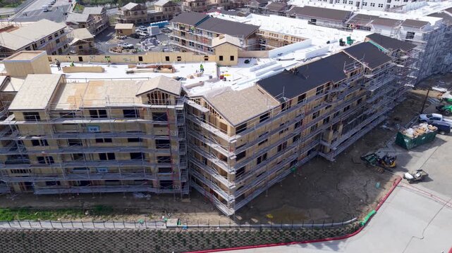 Aerial view shows a residential building project under construction with scaffolding and earthquake resistant techniques in place.