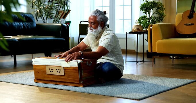 Indian mid age stylish bearded man practicing vocals or singing at home, dedicated to daily riyaz while accompanying harmonium in modern home studio interior setting