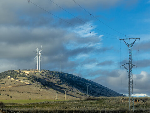 Wind turbines and powerlines in an empty landscape of Soria province, Central Spain, on a partly overcast winter day