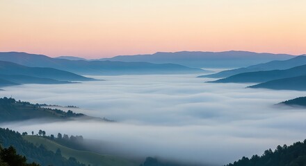Obraz premium Misty mountain landscape at sunrise with foggy valleys and rolling hills under a pinkish sky