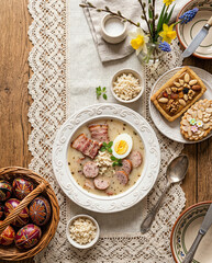 Traditional Polish white borscht with horseradish, egg, sausage, and bacon. The plate sits on a lace table runner. Easter arrangement