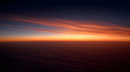 Fototapeta premium Aerial view of a breathtaking sunset painting the sky above a sea of clouds with vibrant orange and blue hues
