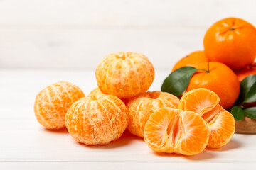 Fresh, ripe, juicy tangerines on the table. Whole and halved tangerines, clementines with green leaves. Citrus fruits. Tangerine or clementine. Fresh oranges. Vitamin C. Natural vitamin. Orange. Space