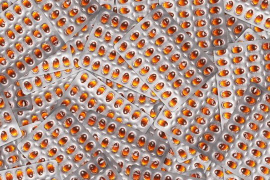 Orange pills texture. Silver blister background. Shiny pharmaceutical foil pattern. Repeating medication packaging layout. Medical tablet surface closeup.