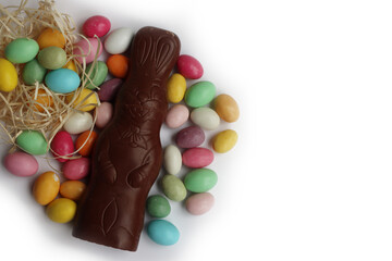 Easter chocolate bunny on white background with many colorful sugar Easter eggs