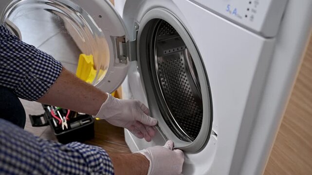 The person in white gloves checks the dirt on the rubber of a washing machine.