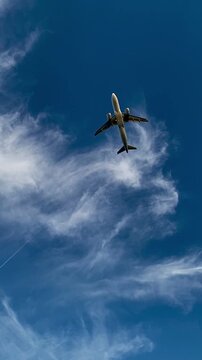 Passenger airplane ascent in blue sky with clouds low angle view