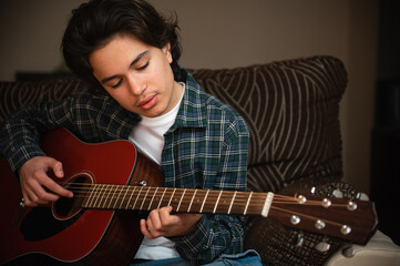 Obraz premium Teenage Boy Playing Acoustic Guitar At Home Cozy Casual Music Practice