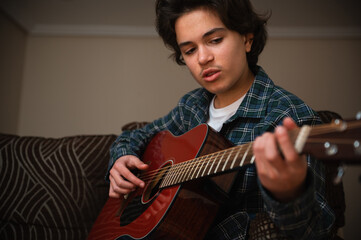 Obraz premium Teenage Boy Playing Acoustic Guitar At Home In Cozy Casual Setting