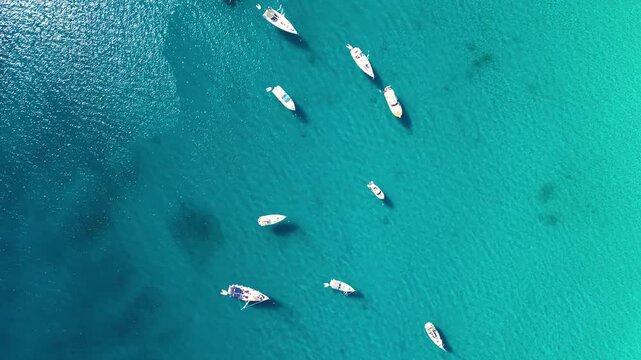Aerial top view of sailboats and yachts anchored in turquoise Adriatic Sea near Croatia. Clear blue water, summer travel destination and peaceful nautical scene.