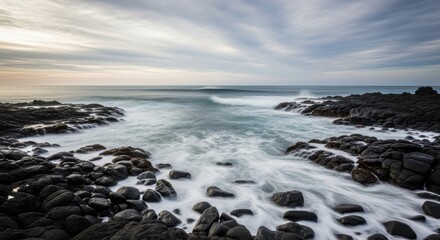 Obraz premium Waves crashing against rugged coastline with rocky shoreline and serene ocean view at dusk
