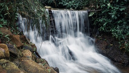 Obraz premium Beautiful small forest waterfall with long exposure silk water effect.